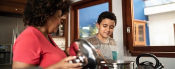 A woman and a boy cook on the stove